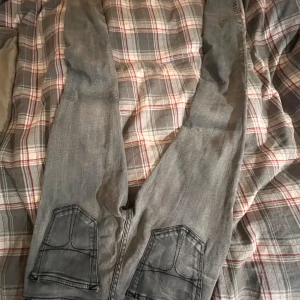 Grå jeansbyxor - Snygga grå jeansbyxor från tiger of sweden  med en klassisk femficksdesign. De har en normal passform och är perfekta för en avslappnad stil. Byxorna har en dragkedja och knapp framtill.