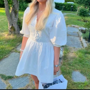 Vit klänning med knappar - Säljer min fina studentklänning från Showpo! Den är endast använd en gång och i ett väldigt fint skick. 