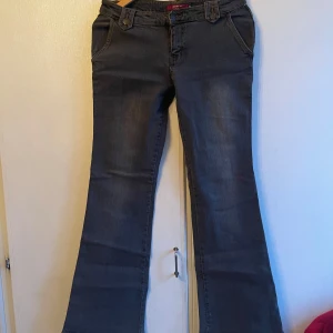 Grå jeans med bälte - Snygga grå/svarta jeans med bootcut-stil och ett coolt bälte i på rumpan. Perfekta för en avslappnad look med en twist. De har en lågmidjad passform och klassiska fickor fram och bak.