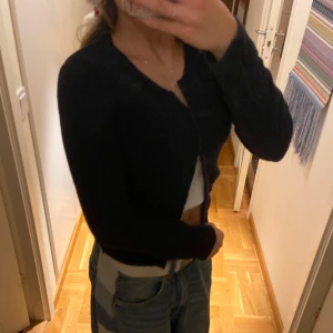 Mörkblå boomerang kofta - Säljer en stilren mörkblå kofta med knappar framtill. Perfekt för lager-på-lager och passar till många olika outfits. Koftan har långa ärmar och en klassisk design.