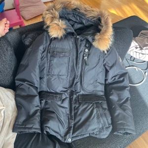 Svart vinterjacka med päls från Hollies - En vinterjacka från Hollies i modell Livigno. I nytt skick och använd 2-3 ggr pga liten. Det är äkta päls som är avtagbar. Priset kan diskuteras vid snabbaffär.