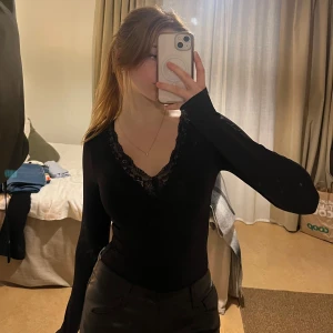 Svart body med spetsringning - Svart body med långa ärmar och v-ringad spetsdetalj i ringningen. Stretchig och bekvämt tyg! Bra kvalite oxå<3