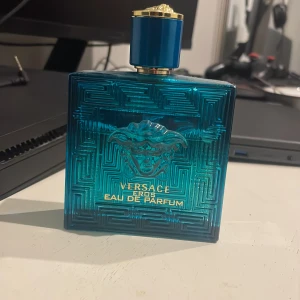 Versace Eros Eau de Parfum - Säljer en flaska Versace Eros Eau de Parfum, 100 ml. Flaskan är i en snygg turkos färg med ett elegant mönster och har en guldig kork med Medusa-loggan. Perfekt för den som vill ha en fräsch och maskulin doft. Flaskan är nästan full och i bra skick. Passa på att köpa denna lyxiga parfym till ett bra pris!