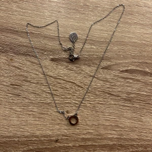 Silverfärgat halsband med cirkelberlock - Snyggt och enkelt silverfärgat halsband med en liten cirkelberlock. Perfekt för både vardag och fest. Kedjan är tunn och smidig med en diskret låsning. Passar till alla outfits och är ett måste i smyckesamlingen! Har stenar på insidan av cirkeln!