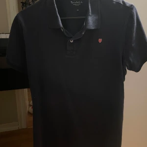 Mörkblå Bondelid piké - En skitnsygg piké från Bondelid som är helt perfekt till sommaren. Den är inte så använd och skicket är bra på den. Storleken är M men den sitter som en S.