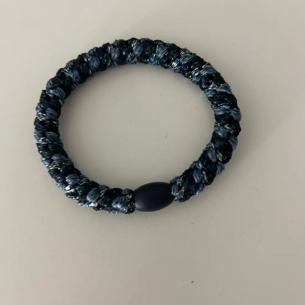 Snyggt svart flätat armband med en glittrig finish. Perfekt för att ge lite extra stil till din outfit. Armbandet har en enkel design med en diskret svart låsdetalj. Passar både till vardags och festliga tillfällen.. Accessoarer.