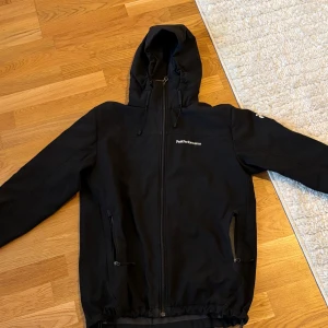 Svart jacka från Peak Performance - Säljer en svart jacka från Peak Performance i mycket bra skick. Den har en dragkedja framtill och två fickor med dragkedjor. Jackan har en huva och är perfekt för höst och vår. Den är långärmad och har en normal passform. Perfekt för vardagsbruk eller en promenad i parken.