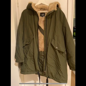 Olivgrön parkajacka med fuskpälsfoder - Säljer en olivgrön parkajacka från TRF Collection. Den har ett mysigt fuskpälsfoder som håller dig varm under kalla dagar. Jackan har en dragkedja framtill och praktiska fickor. Helt ny!