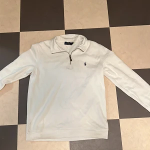  Vit Haf Zip Hoodie från Polo Ralph Lauren - Säljer en stilren vit haf zip  hoodie från Polo Ralph Lauren i storlek s. Tröjan är i bomull och har en dragkedja vid halsen. Perfekt för en avslappnad men ändå snygg look. Den har långa ärmar och är i bra skick . Passar perfekt till både vardag och fest!  !Vet ej om den e äkta! Priser ej hugget i sten