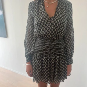 Mönstrad klänning med midjedetalj - Säljer en superfin mönstrad klänning med smockdetaljer i midjan. Använd 1 gång så den är i väldigt fint skick