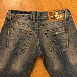 Low waist jeans med slitningar - Säljer ett par snygga blå low waisted vintage jeans i bootcut och utmärkt skick. De har en cool slitningseffekt och klassiska femficksdesign. Passar bra till både sneakers och boots! Innerbenslängden är 74 cm och midjemått 36cm 💕Dom går inte längre att köpa i butik och priset kan diskuteras lite 💕