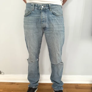 Blå jeans med slitningar - Säljer ett par klassiska blå karve jeans i bra skick. De har en straight passform och är midwaist. Jeansen har coola slitningar på knäna som ger en avslappnad look. Perfekta för både vardag och fest!