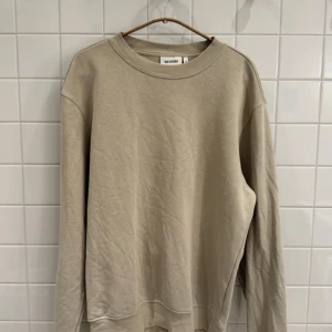 Beige sweatshirt från Weekday - Storlek S - Säljer en stilren beige sweatshirt från Weekday i mycket bra skick. Den har en klassisk rund hals och långa ärmar, perfekt för både höst och vår. Materialet är mjukt och bekvämt, vilket gör den idealisk för vardagsbruk. Passar perfekt till jeans eller chinos!