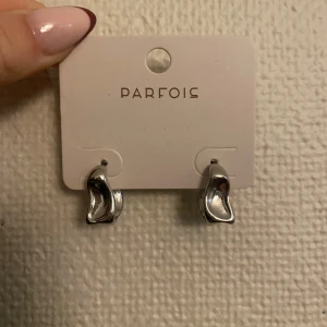 Silverörhängen från Parfois - Snygga och stilrena silverörhängen från Parfois. De har en unik, böljande form som ger en modern touch till vilken outfit som helst. Perfekta för både vardag och fest! Köpta för 6€ så ungefär 70 svenska kronor helt oanvända. kolla min profil efter flera saker om ni köper flera får ni rabatt!!!