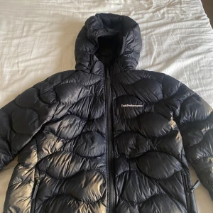 Svart dunjacka från Peak Performance - Säljer en svart dunjacka från Peak Performance i mycket bra skick. Storlek 170 men sitter som en XS-S. Luvan går att ta av. Nypris 2000kr