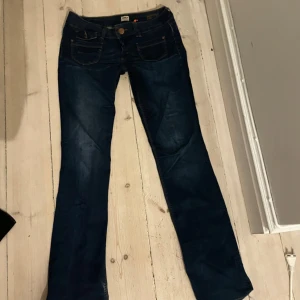 Mörkblå bootcut jeans från ONLY - Säljer ett par snygga mörkblå bootcut jeans från ONLY. De har en låg midja och klassisk femficksdesign. Lite små defekter där nere men annars perfekta! Passar 36/38, exakta mått vet jag inte men jag tror 28 