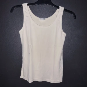 Beige linnetopp från H&M - Säljer en enkel och stilren vit linnetopp från H&M i storlek 40-42 (M) liten i storleken. Perfekt för sommardagar eller som ett basplagg i garderoben. Toppen är ärmlös och gjord i ett mjukt och bekvämt material.