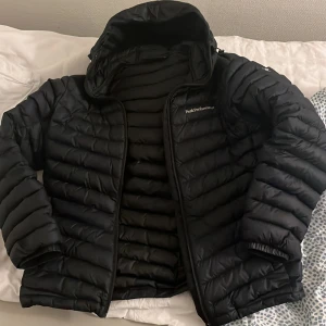 Svart pufferjacka från Peak Performance - Säljer en svart pufferjacka från Peak Performance i mycket bra skick. Jackan är perfekt för kalla dagar med sin varma vaddering och har en praktisk dragkedja framtill. Den är långärmad och har en stilren design som passar både till vardags och utomhusaktiviteter.