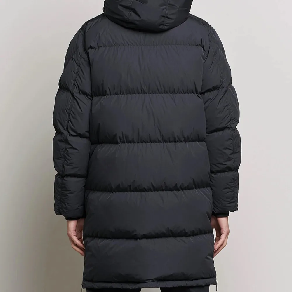 Säljer en svart lång dunjacka från Parajumpers med huva och knäppning framtill. Jackan har en broderad logga på ärmen och stora fickor. Perfekt för kalla dagar. Ny pris 9990kr.. Takit.