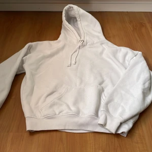 Vit hoodie med ficka - Säljer en klassisk vit hoodie med stor ficka framtill och justerbar huva. Perfekt för en avslappnad stil. Passar bra till jeans eller mjukisbyxor. Hör av dig vid intresse!