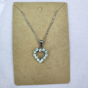 Halsband med hjärtformad berlock - Elegant halsband med en hjärtformad berlock dekorerad med gnistrande stenar. Kedjan är i silverfärg och berlocken har en öppen design som ger en stilren look. Perfekt för att lägga till en touch av glamour till din outfit. Äkta silver.