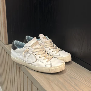 Vita sneakers från Philippe Model - Snygga vita sneakers från Philippe Model med svarta detaljer på hälen. Skorna har en klassisk design med snörning och en bekväm passform. Perfekta för en stilren look. Nypris på skorna är 3800kr. Skorna är i storlek 37 men är stora i storleken så passar också 38. Pris kan diskuteras👍