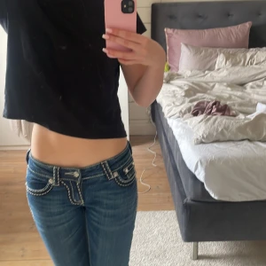 Blå jeans från Miss Me - Snygga blå jeans från Miss Me med dekorativa sömmar och detaljer på bakfickorna. Jeansen har en lågmidjad passform och bootcut.