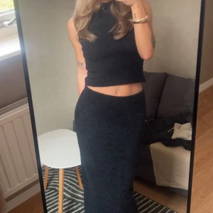 Svart stickad set - Ett snyggt och bekvämt stickat set köpt från Nelly, endast använt ett fåtal gånger. Slits där bak på kjolen. Strl S på både kjolen och toppen. Säljs tillsammans🤍