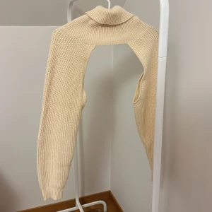 Beige stickad polotröja från ASOS - Säljer en beige stickad polotröja från ASOS. Tröjan har en unik design med långa ärmar och en hög polokrage. Perfekt för att hålla sig varm under kyliga dagar. Passar bra till både jeans och kjol.