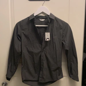 Svart skjorta från Cubus - Snygg svart skjorta från märket C i storlek 146. Skjortan har långa ärmar och knappar framtill. Perfekt för en stilren look. Ny köpt men för liten