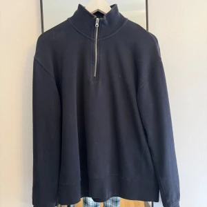 Svart tröja med dragkedja från Zara - Säljer en svart tröja från Zara med halv dragkedja och hög krage. Tröjan har långa ärmar och en avslappnad passform. Perfekt för kyligare dagar. Observera att det finns ett hål på ena ärmen.