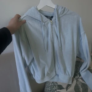 Ljusblå hoodie med dragkedja - Säljer en ljusblå hoodie från Bik Bok med dragkedja och huva. Den har långa ärmar och ribbade muddar vid ärmslut och nederkant. Perfekt för en avslappnad stil. Aldrig använd 😊