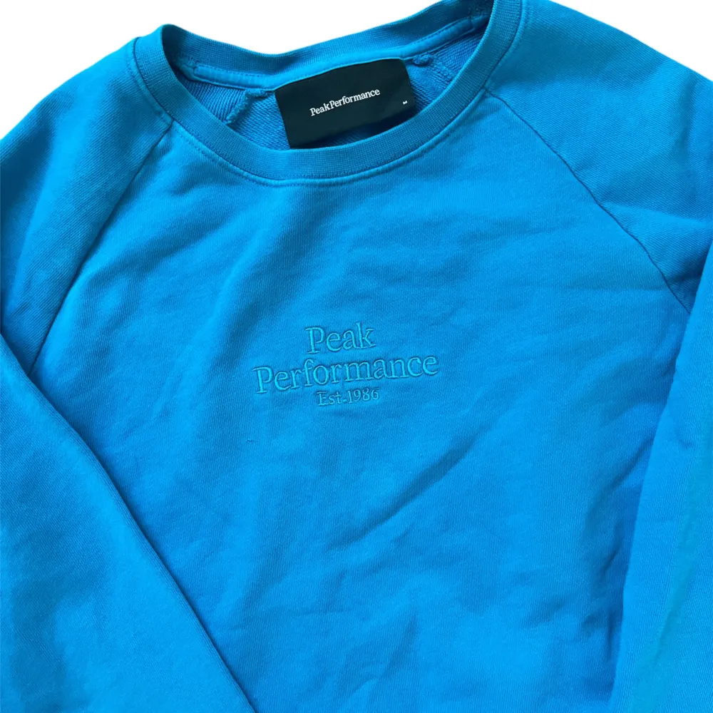 💎En snygg blå tröja från Peak Performance. Tröjan har en broderad logga på bröstet och är tillverkad i ett mjukt material. 📬Skickas inom 24 timmar!. Neuletakit & Villapaidat.