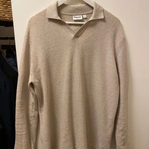 Beige stickad tröja från Kappahl - Säljer en stilren beige stickad tröja från Kappahl. Tröjan har en klassisk krage och långa ärmar, perfekt för kyligare dagar. Den är mjuk och bekväm, idealisk för både vardag och avslappnade tillfällen. Passar bra till jeans eller chinos.