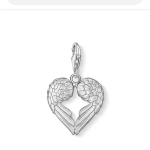 Silverfärgat hängsmycke med änglavingar - Charmig berlock från Tomas sabo. berlocken är i äkta silver. OBS den är sönder. Original pris 450kr