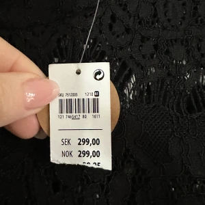 Ny Svart spetsklänning från Lindex - Elegant svart klänning från Lindex med vackra spetsdetaljer på ärmar och överdel. Perfekt för en stilren look. Klänningen har långa ärmar och en normal passform.