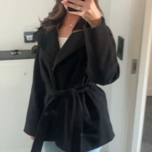 Svart kappa med knytband - Intressekoll på min snygga svart kappa med knytband i midjan. Perfekt för höst och vår. Den har långa ärmar och en stilren design som passar till många olika outfits.