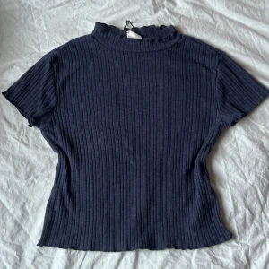 Mörkblå ribbad topp från Zara - mörkblå ribbad topp från Zara. Toppen har korta ärmar och en hög halsringning, väldigt stretchigt material så passarna allt från s-litet m. Köpt för flera år sen så går inte att hitta längre men knappt använd🫶