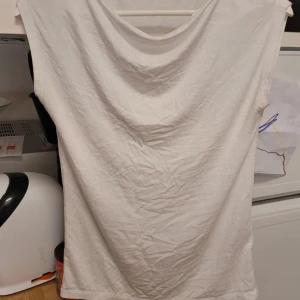 Vit ärmlös topp - Säljer en enkel och stilren vit ärmlös topp. Perfekt för varma dagar eller som ett basplagg i garderoben. Toppen har en mjuk och bekväm passform.
