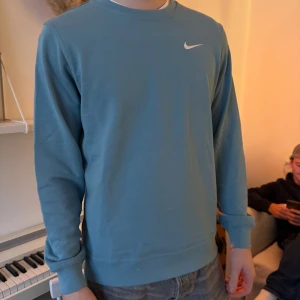 Nike sweatshirt - Säljer en stilren blå sweatshirt från Nike med rund hals och långa ärmar. Den har en liten Nike-logga broderad på bröstet. Har små defekter som syns på sista bilden!