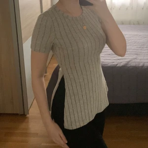 Grå topp - Säljer en stilren grå topp med korta ärmar. Toppen har en figurnära passform och är perfekt för en avslappnad look. Den är enkel att matcha med olika outfits.