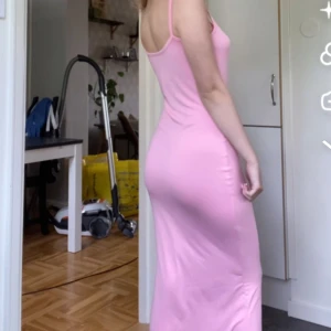 Rosa långklänning - Snygg rosa långklänning med smala axelband. Perfekt för en somrig look. Klänningen har en tight passform som framhäver figuren.