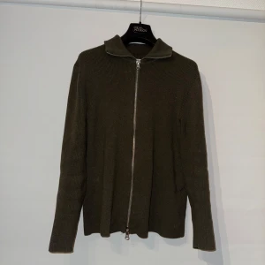 Olivgrön stickad tröja från Ljung - Säljer en olivgrön stickad tröja från Ljung by Marcus Larsson. Tröjan har en dragkedja framtill och långa ärmar. Köpt för 1000 och använt fåtal gånger!