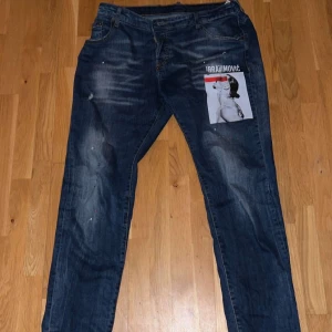 Blå jeans med tryck från Dsquared2 - Snygga blå jeans från Dsquared2 med ett unikt tryck på framsidan. Jeansen har en klassisk femficksdesign och slitna detaljer för en cool look. Perfekta för dig som vill sticka ut med stil.