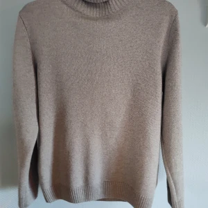 Beige stickad polotröja från Stenströms - Säljer en stilren beige stickad polotröja från Stenströms i nästintill nyskick. Tröjan har långa ärmar och en klassisk polokrage. Den är mjuk, bekväm och skön, vilket gör den till ett utmärkt val för både vardag och mer uppklädda tillfällen.