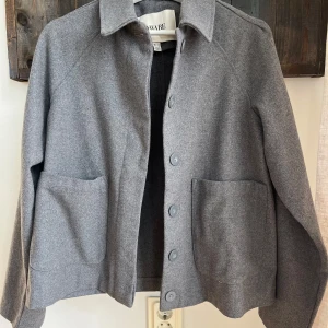 Grå ulljacka från AWARE - Säljer en stilren grå jacka från AWARE. Jackan knäpps med knappar framtill samt att den har två stora fickor på framsidan och är perfekt för höst- och vårsäsongen. Passformen är normal och den är långärmad🥰