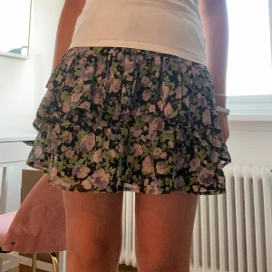 Blommig volangkjol - Säljer en superfin kort blommig kjol med volanger! 🖤💜💚