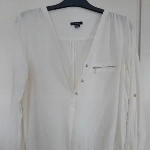 Vit blus  - Vit v-ringad blus  T-shirt material  Fina detaljer uppe vid kragen och vid ärmarna  Storlek L