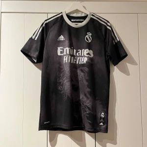 Adidas: Real Madrid x Human Race collab svart/grå - Sparsamt använd och väl omhändertagen, ser och känns som ny! Sällsynt Real Madrid träningsplagg som många inte ens känner till. RM collab med Pharrell Williams klädesmärke ”Human Race”. Först till kvarn!   Butikpris: 2 299kr 