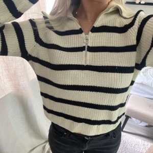 Randig stickad tröja från Lindex - Säljer en superfin stickad tröja från Lindex i storlek S💘Den är beige/vit med svarta ränder och har en dragkedja framtill. Perfekt för hösten 🍁🍂Tröjan är långärmad och har en normal passform. 